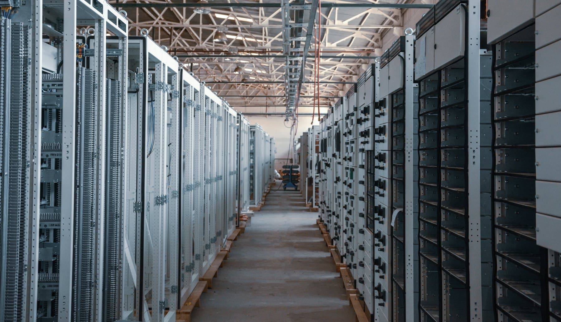 A long aisle between rows of white equipment cabinets in a server room
